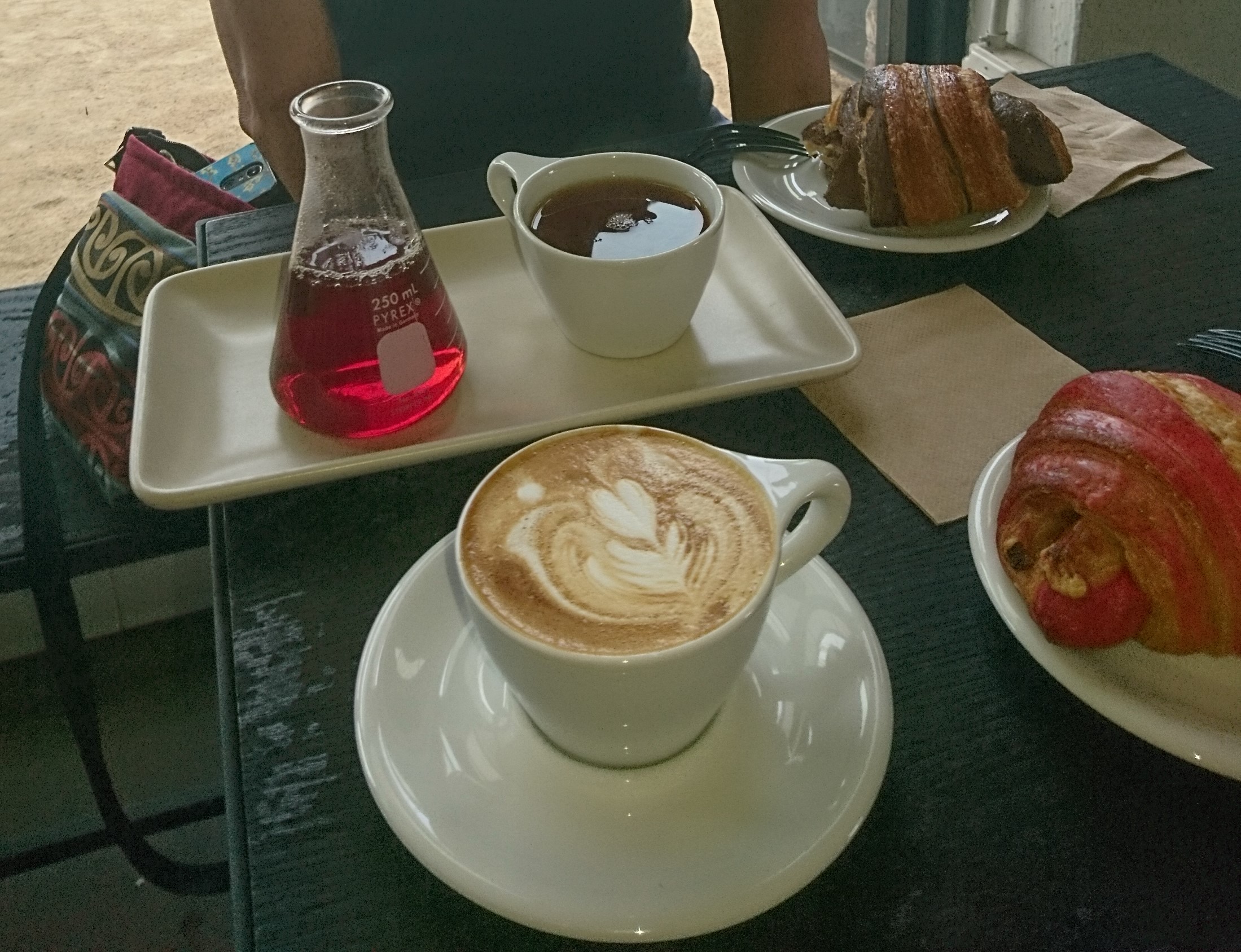 Tea in a flask and a cup, a cappuccino, and two pastries