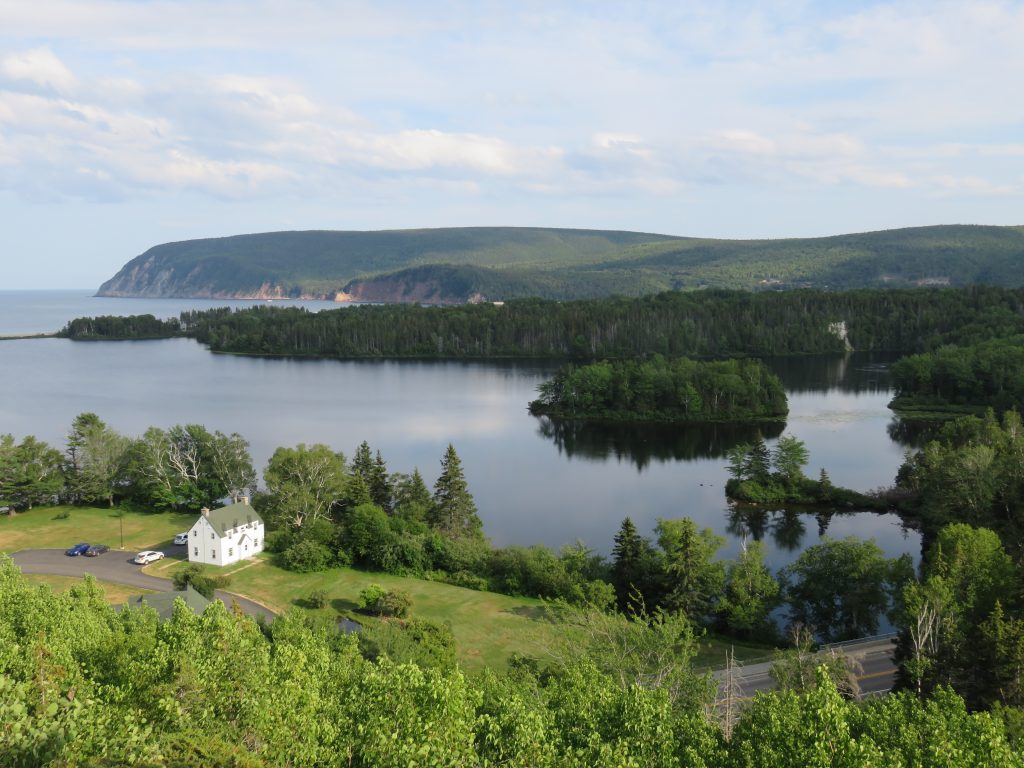 View of a lake with a wooded island and cliffs in the distance.