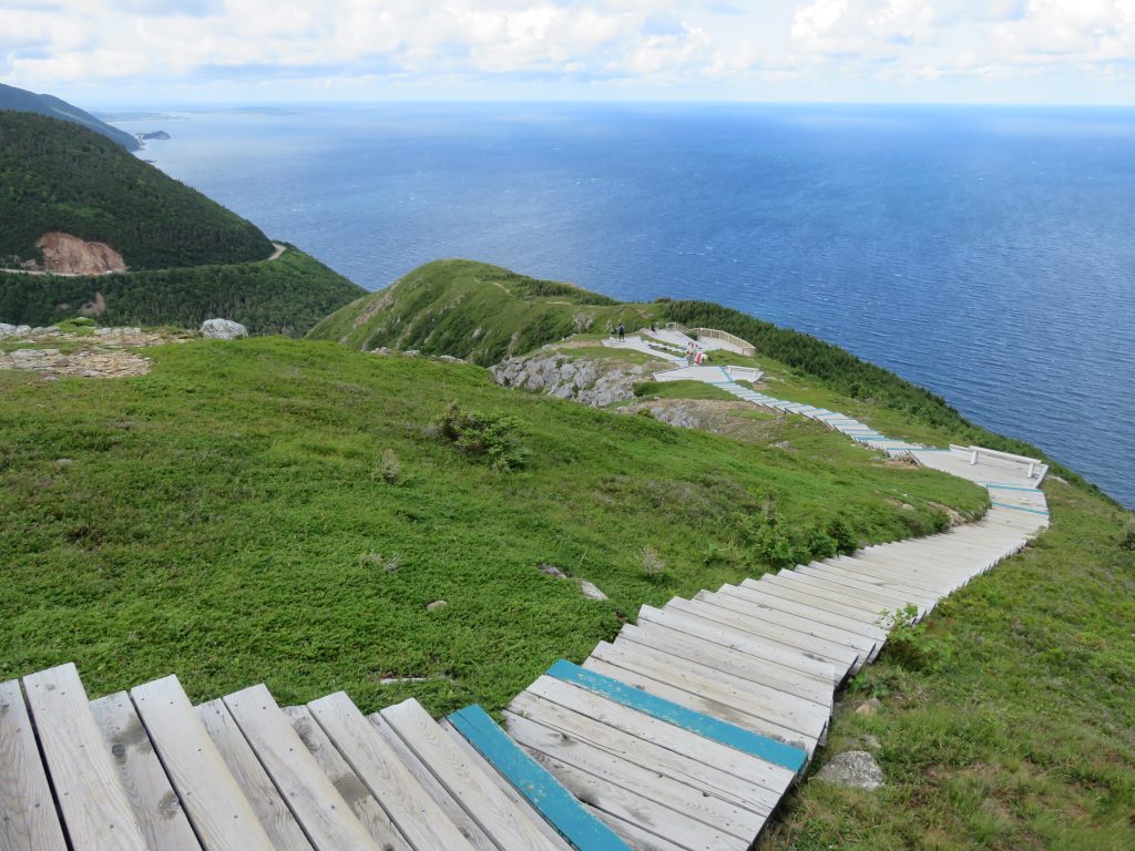 Wooden staircase leading down to a viewpoint looking out over a cliff to the ocean.