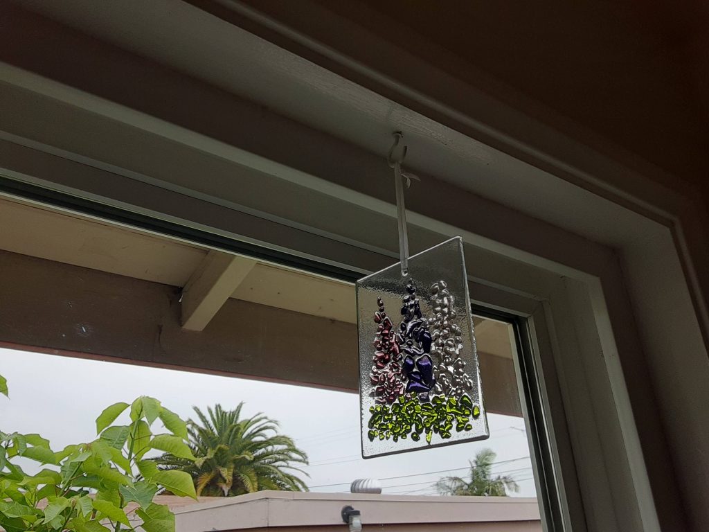 A rectangle of clear glass with three shades of purple flowers on it.